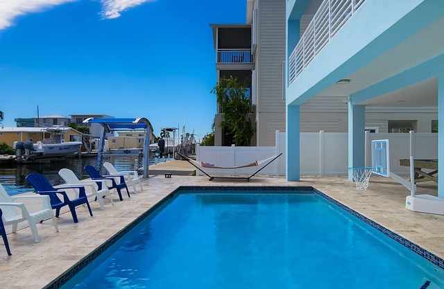 Sprawling waterfront home with pool, outdoor kitchen, game table, grill, & W/D